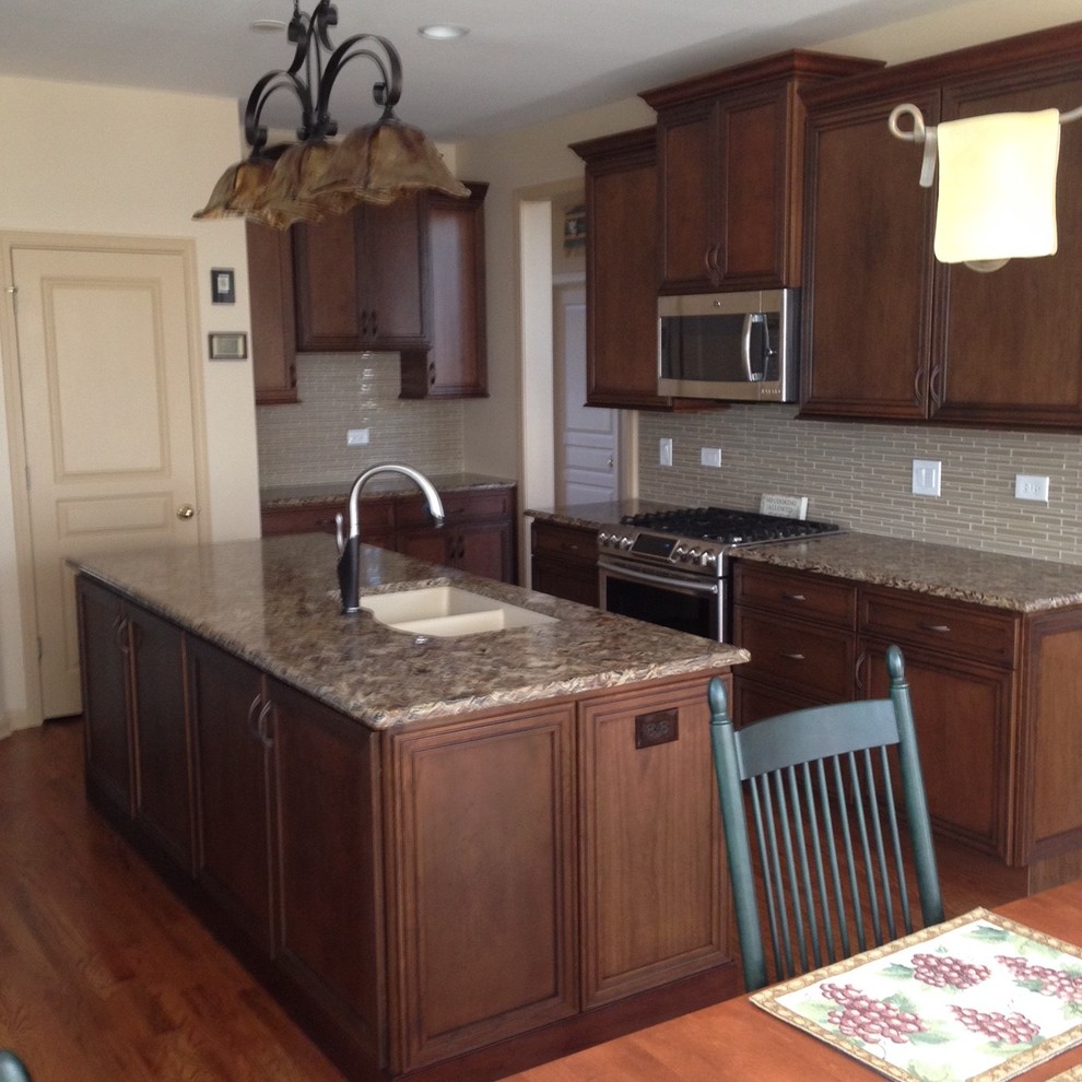 Eat-in kitchen - mid-sized transitional medium tone wood floor and brown floor eat-in kitchen idea in Chicago with a double-bowl sink, recessed-panel cabinets, medium tone wood cabinets, quartz countertops, beige backsplash, glass sheet backsplash, stainless steel appliances and an island