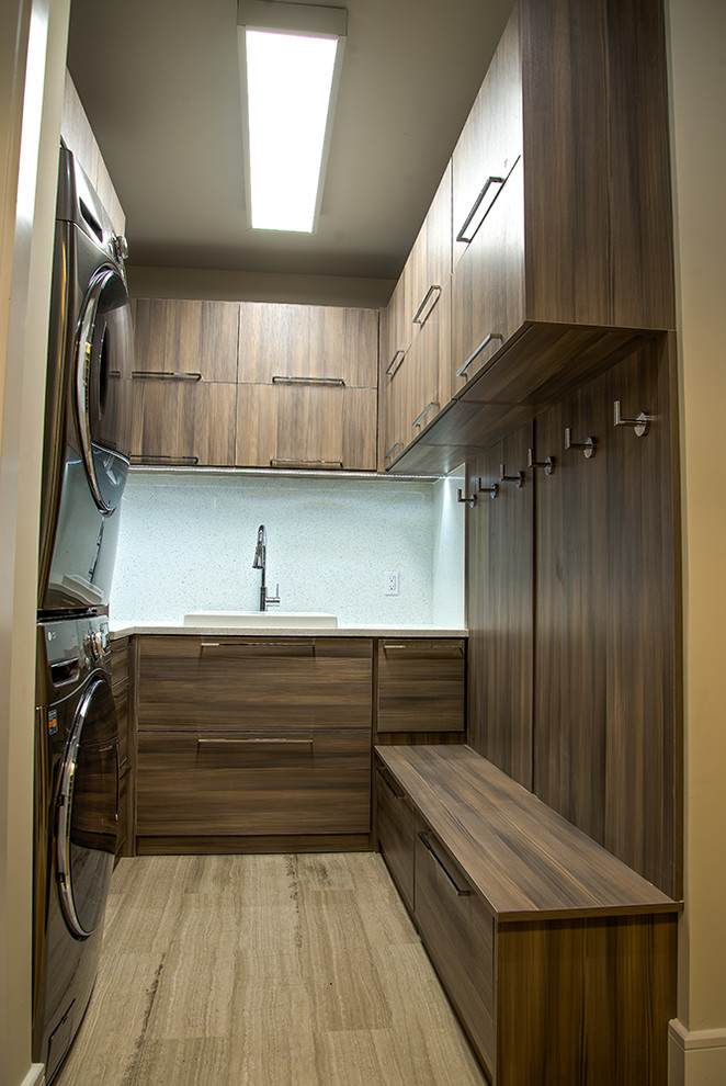 Mid-sized modern u-shaped dedicated laundry room in Miami with flat-panel cabinets, dark wood cabinets, a stacked washer and dryer, a drop-in sink, porcelain floors and beige floor.