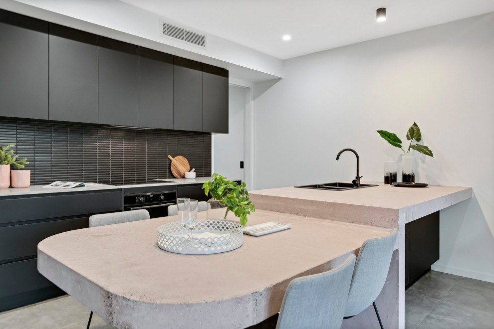 Design ideas for a contemporary kitchen in Sunshine Coast with a double-bowl sink, flat-panel cabinets, black cabinets, black splashback, matchstick tile splashback, black appliances, a peninsula, grey floor and beige benchtop.