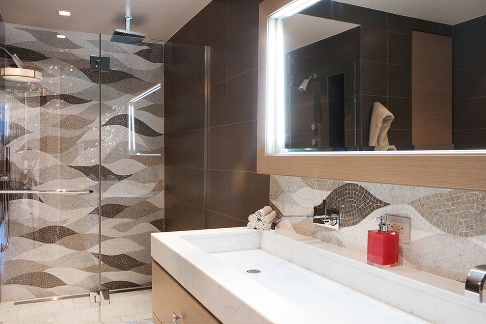 Contemporary bathroom in New York with a trough sink, flat-panel cabinets, light wood cabinets, an alcove shower, multi-coloured tile and mosaic tile.