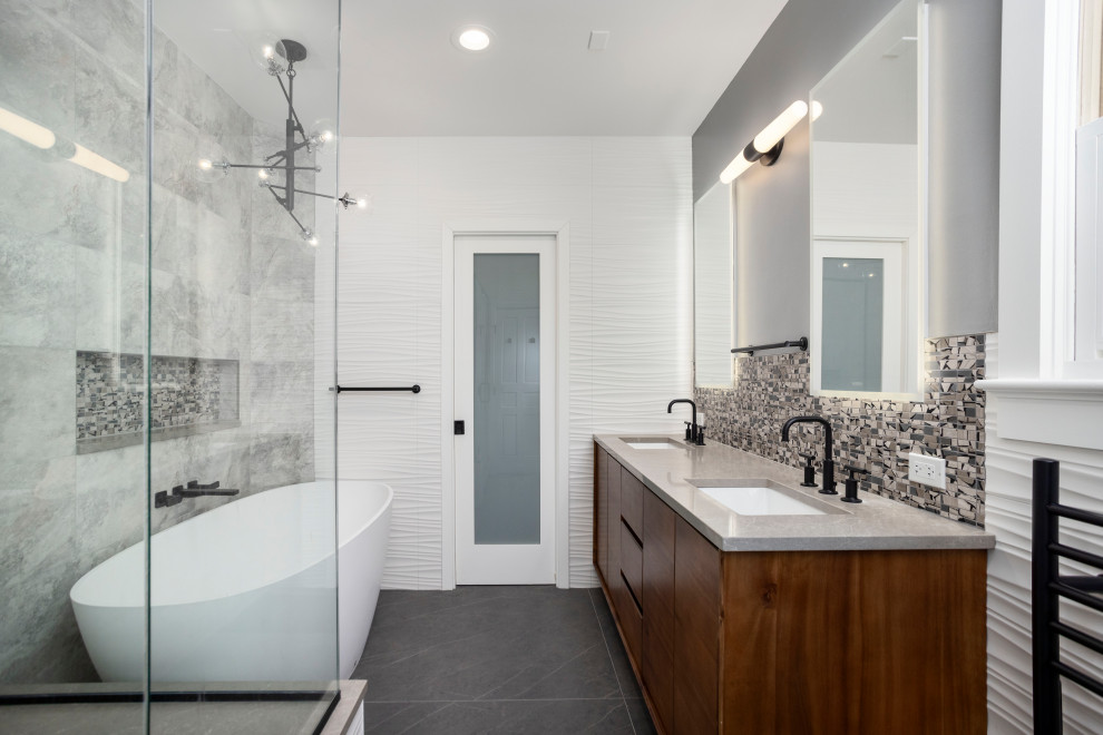 Design ideas for a large contemporary ensuite bathroom in Chicago with medium wood cabinets, a freestanding bath, grey tiles, ceramic tiles, engineered stone worktops, black floors, grey worktops, a wall niche, double sinks and a freestanding vanity unit.