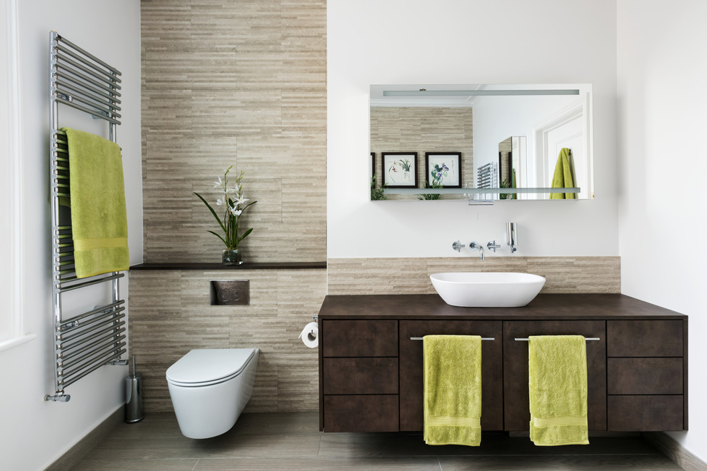 Inspiration for a contemporary master bathroom in London with flat-panel cabinets, brown cabinets, a wall-mount toilet, beige tile, white walls, a vessel sink and grey floor.