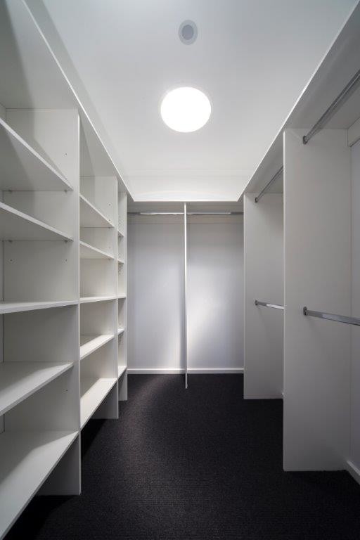 Inspiration for a mid-sized contemporary gender-neutral walk-in wardrobe in Canberra - Queanbeyan with open cabinets, white cabinets, carpet and black floor.