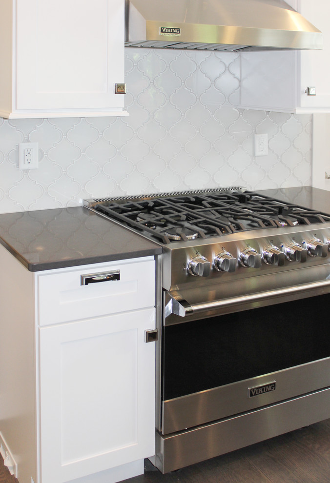 Kitchen - transitional dark wood floor kitchen idea in Cedar Rapids with shaker cabinets, white cabinets, quartzite countertops, white backsplash, porcelain backsplash and stainless steel appliances