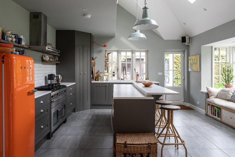 Design ideas for a mid-sized beach style l-shaped kitchen in Sussex with a double-bowl sink, grey cabinets, white splashback, stainless steel appliances, with island, grey floor, white benchtop, shaker cabinets and subway tile splashback.
