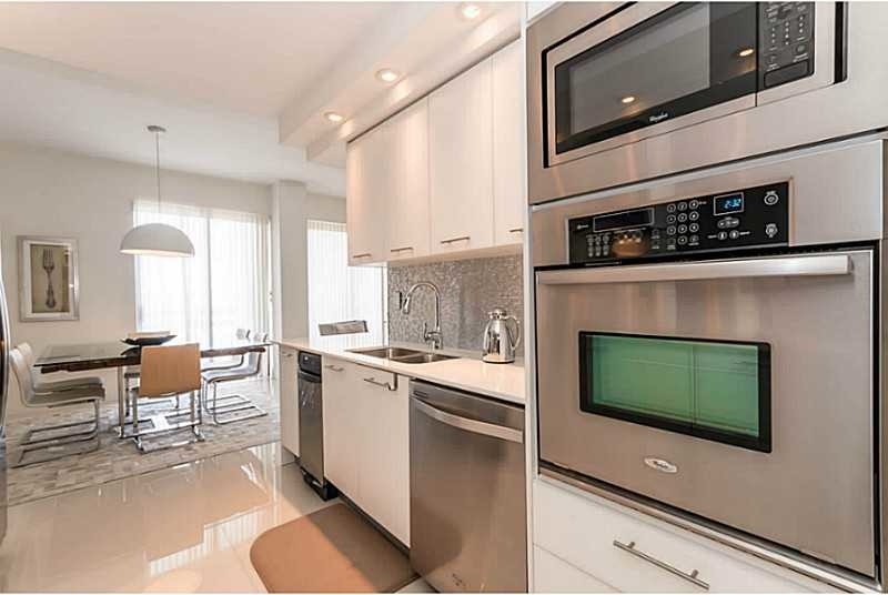 Inspiration for a mid-sized modern galley eat-in kitchen in Miami with a double-bowl sink, flat-panel cabinets, white cabinets, quartz benchtops, multi-coloured splashback, mosaic tile splashback, stainless steel appliances, linoleum floors, a peninsula and beige floor.