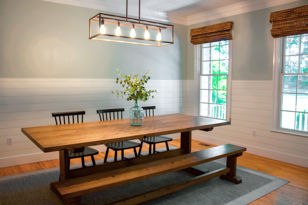 Cette photo montre une grande salle à manger ouverte sur la cuisine nature avec un mur vert, un sol en bois brun, aucune cheminée, un sol marron et du lambris de bois.