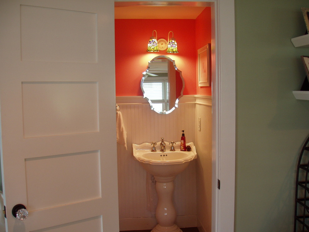 Photo of a small traditional 3/4 bathroom in Baltimore with a pedestal sink, a one-piece toilet, orange walls and dark hardwood floors.