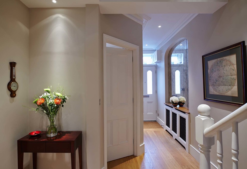This is an example of a large transitional hallway in London with beige walls and medium hardwood floors.