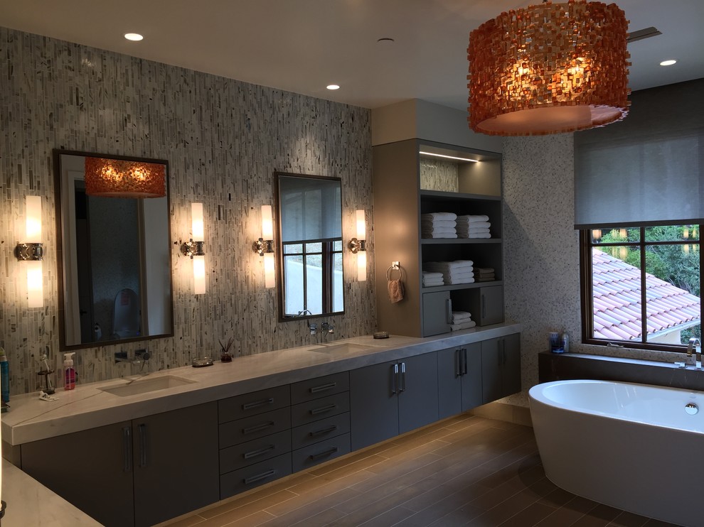 This is an example of a large contemporary master bathroom in San Francisco with an undermount sink, flat-panel cabinets, grey cabinets, marble benchtops, a freestanding tub, a curbless shower, a one-piece toilet, brown tile, porcelain tile, white walls and porcelain floors.