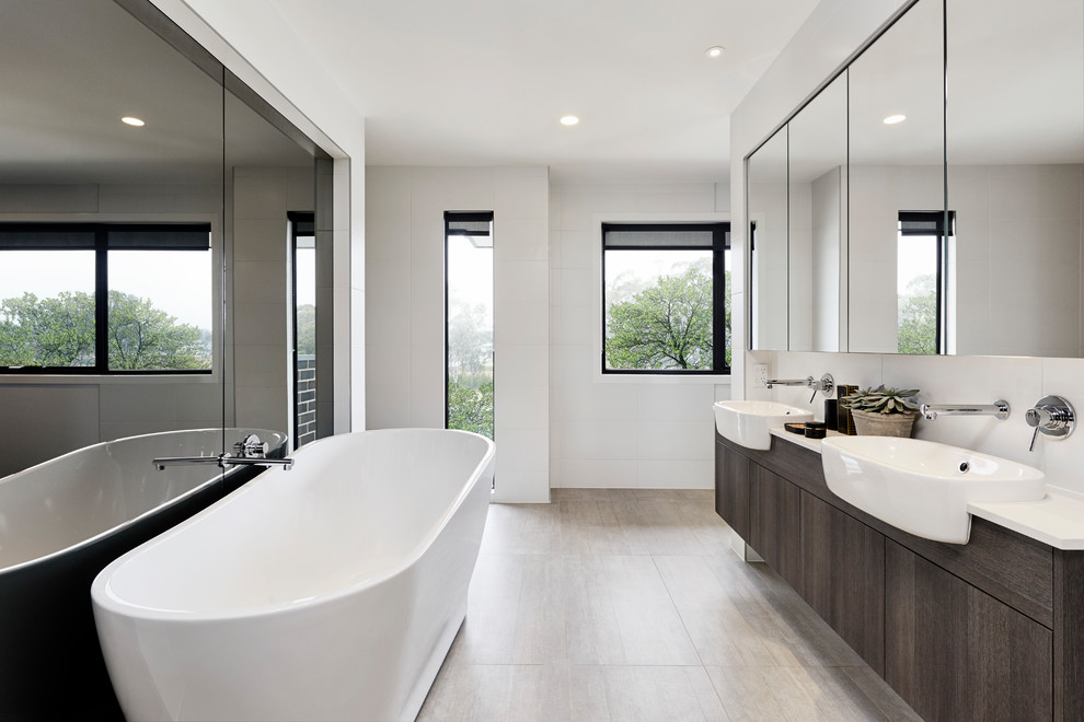 Inspiration for a modern master bathroom in Sydney with flat-panel cabinets, dark wood cabinets, a freestanding tub, white walls, a drop-in sink and grey floor.