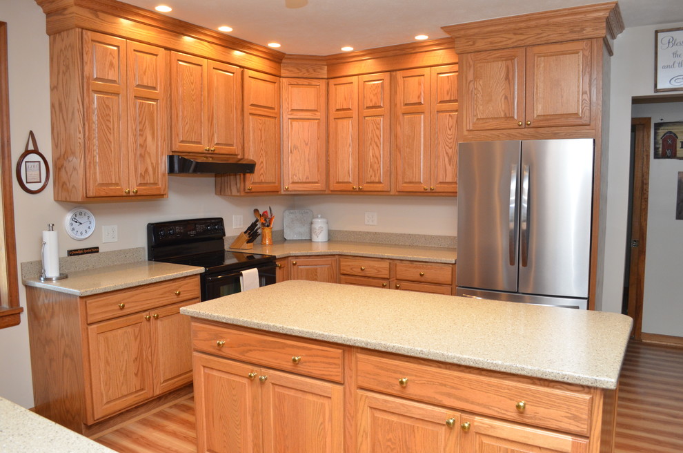 Photo of a mid-sized traditional l-shaped separate kitchen in Other with solid surface benchtops, with island, an undermount sink, raised-panel cabinets, light wood cabinets, light hardwood floors, brown floor and beige benchtop.