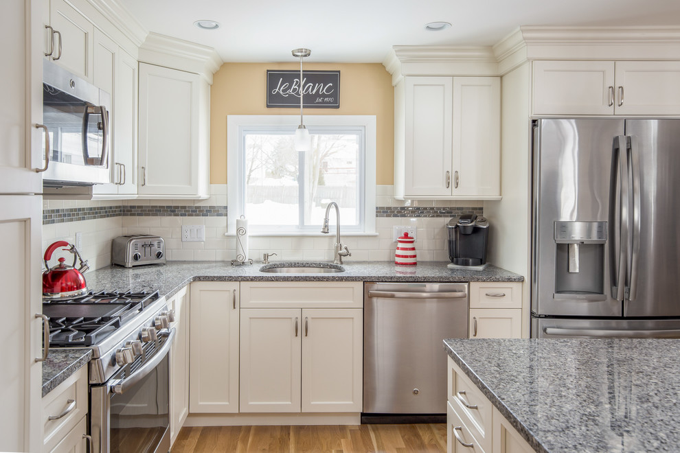 Small transitional l-shaped eat-in kitchen in Boston with an undermount sink, shaker cabinets, yellow cabinets, granite benchtops, multi-coloured splashback, subway tile splashback, stainless steel appliances, light hardwood floors and with island.