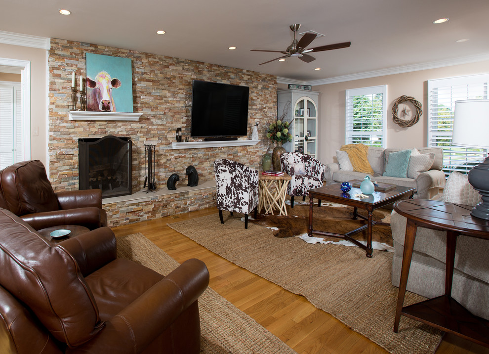 Inspiration for a large country enclosed living room in DC Metro with beige walls, medium hardwood floors, a standard fireplace, a stone fireplace surround, a freestanding tv and brown floor.