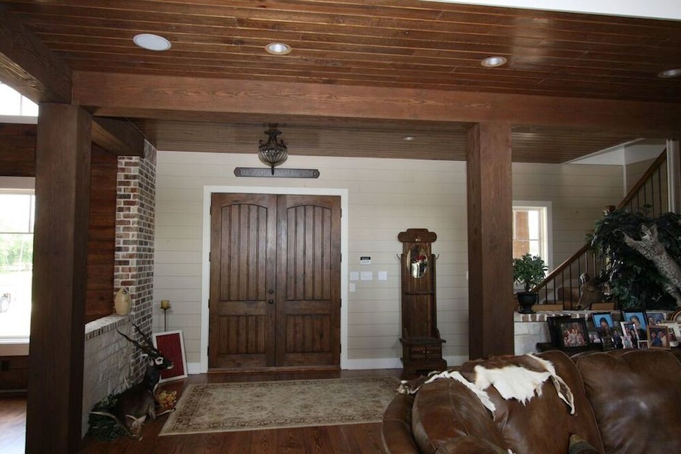 Example of a small mountain style medium tone wood floor and brown floor front door design with beige walls and a dark wood front door