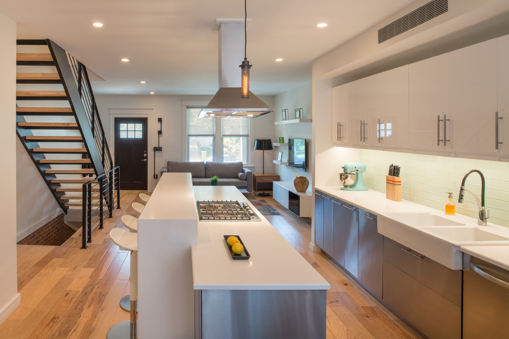 Design ideas for a small modern single-wall eat-in kitchen in DC Metro with a farmhouse sink, flat-panel cabinets, stainless steel cabinets, quartzite benchtops, white splashback, subway tile splashback, stainless steel appliances, light hardwood floors and with island.