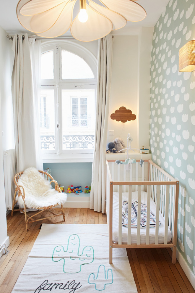 Design ideas for a small eclectic nursery for boys in Paris with green walls, medium hardwood floors and wallpaper.