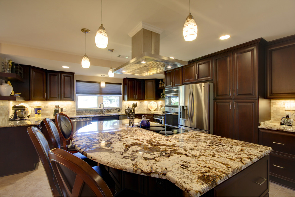 Eat-in kitchen - large transitional l-shaped porcelain tile eat-in kitchen idea in Miami with an undermount sink, raised-panel cabinets, dark wood cabinets, granite countertops, beige backsplash, stone tile backsplash, stainless steel appliances and an island