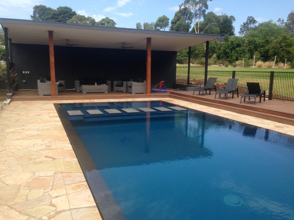 Inspiration for a large contemporary backyard rectangular pool in Melbourne with natural stone pavers.