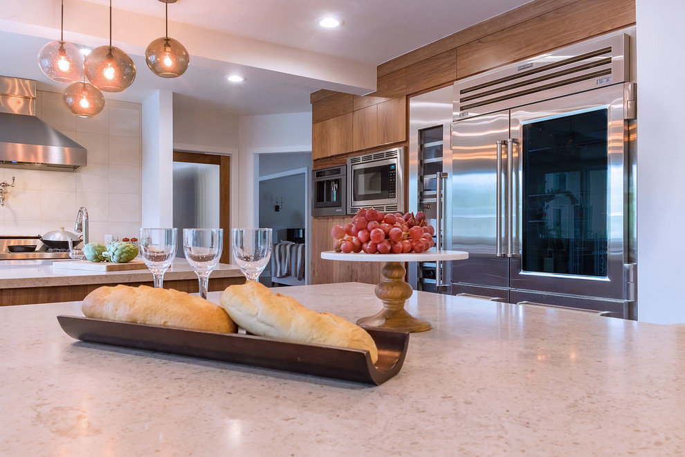 Inspiration for an expansive contemporary u-shaped eat-in kitchen in Los Angeles with flat-panel cabinets, medium wood cabinets, limestone benchtops, beige splashback, porcelain splashback, multiple islands, an undermount sink, stainless steel appliances, medium hardwood floors and brown floor.