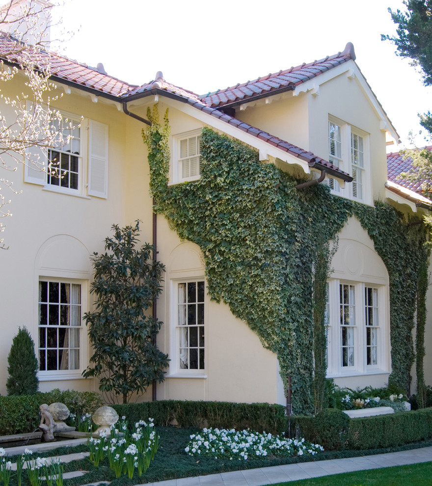 Large traditional two-storey stucco beige house exterior in Dallas with a tile roof.