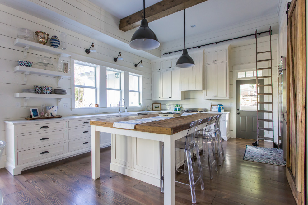Inspiration for a country l-shaped kitchen in Atlanta with a farmhouse sink, shaker cabinets, white cabinets, wood benchtops, timber splashback, stainless steel appliances, dark hardwood floors, with island, brown floor, brown benchtop and exposed beam.