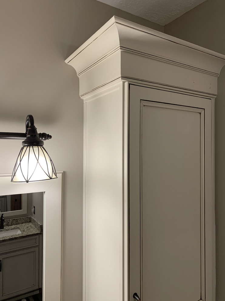 Inspiration for a large transitional master beige tile and ceramic tile linoleum floor and brown floor home design remodel with recessed-panel cabinets, white cabinets, a two-piece toilet, beige walls, an undermount sink, granite countertops, a hinged shower door and multicolored countertops