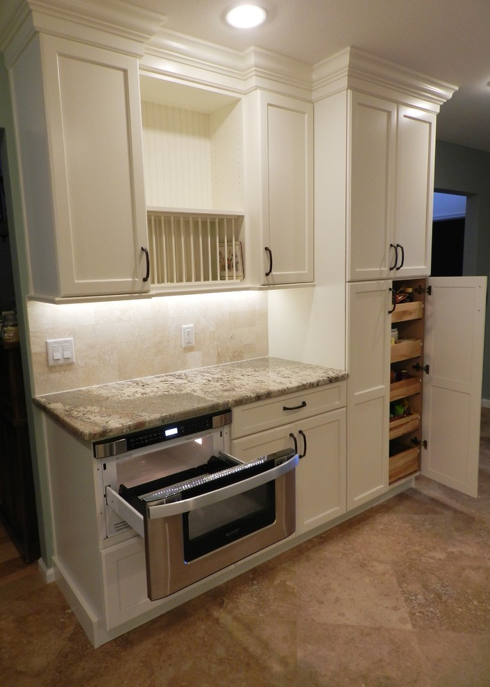 Inspiration for a mid-sized traditional u-shaped eat-in kitchen in Jacksonville with an undermount sink, shaker cabinets, white cabinets, granite benchtops, beige splashback, stone tile splashback, stainless steel appliances, travertine floors and no island.