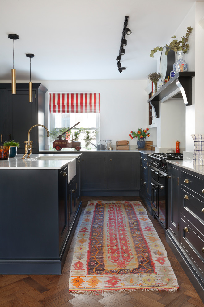 Zweizeilige Wohnküche mit Landhausspüle, Schrankfronten im Shaker-Stil, blauen Schränken, Quarzit-Arbeitsplatte, dunklem Holzboden, Kücheninsel, braunem Boden und weißer Arbeitsplatte in London