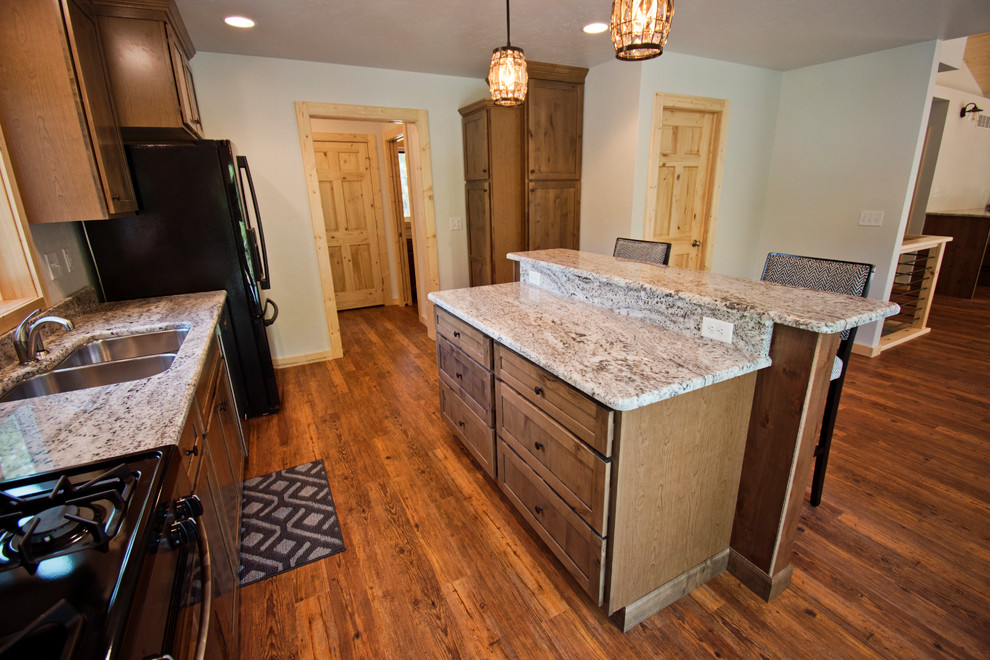 Mid-sized mountain style galley medium tone wood floor and brown floor eat-in kitchen photo with a double-bowl sink, recessed-panel cabinets, brown cabinets, granite countertops, stainless steel appliances, an island and beige countertops
