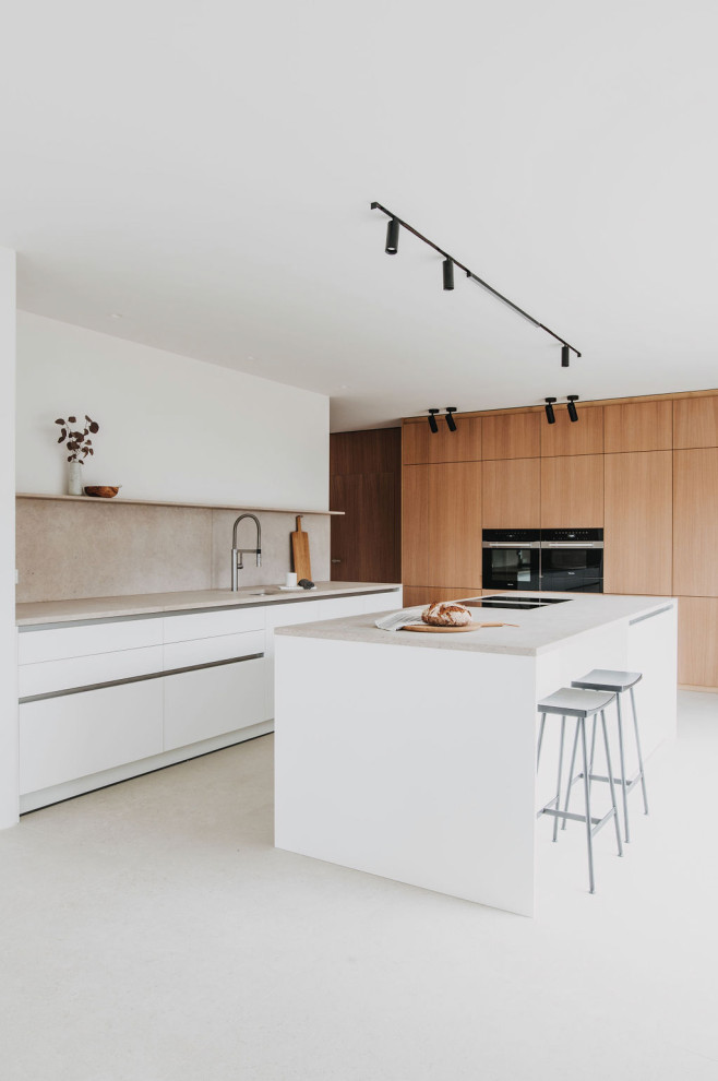 This is an example of a large contemporary eat-in kitchen in Munich with an undermount sink, flat-panel cabinets, light wood cabinets, limestone benchtops, beige splashback, limestone splashback, black appliances, with island, beige floor and beige benchtop.
