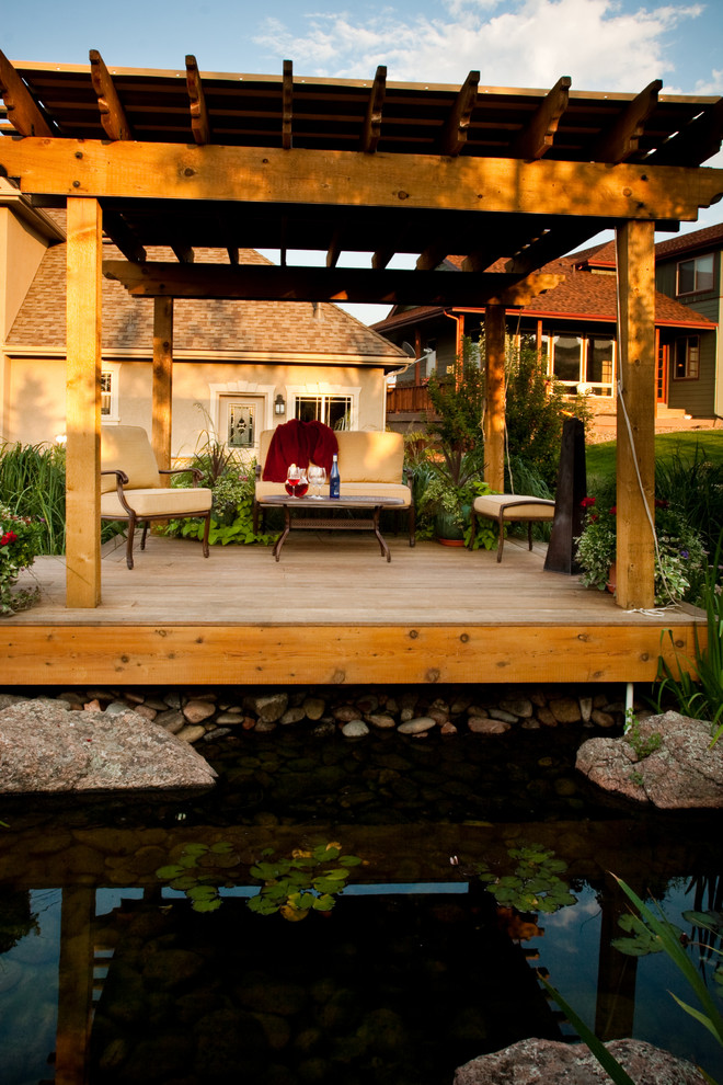 Large traditional backyard deck in Denver with a water feature and a pergola.