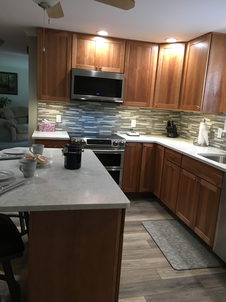 Kitchen - mid-sized transitional l-shaped laminate floor and gray floor kitchen idea in Boston with an undermount sink, shaker cabinets, light wood cabinets, quartz countertops, multicolored backsplash, glass sheet backsplash, stainless steel appliances, an island and white countertops