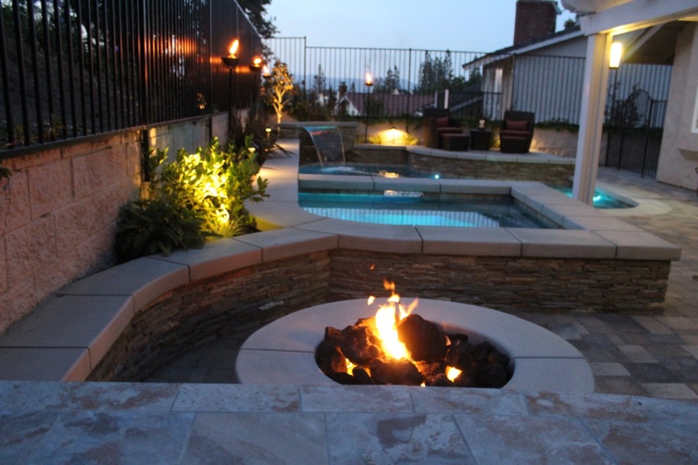 Photo of a mid-sized traditional backyard custom-shaped pool in Orange County with a water feature and concrete pavers.