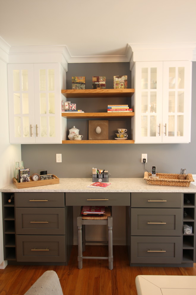 Example of a mid-sized transitional u-shaped medium tone wood floor and brown floor enclosed kitchen design with a farmhouse sink, shaker cabinets, white cabinets, quartz countertops, white backsplash, subway tile backsplash, white appliances, no island and beige countertops