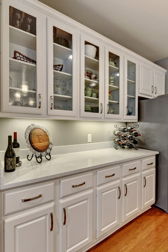 Inspiration for a mid-sized transitional u-shaped light wood floor eat-in kitchen remodel in Austin with an undermount sink, white cabinets, quartz countertops, white backsplash, stone slab backsplash, stainless steel appliances, a peninsula and raised-panel cabinets