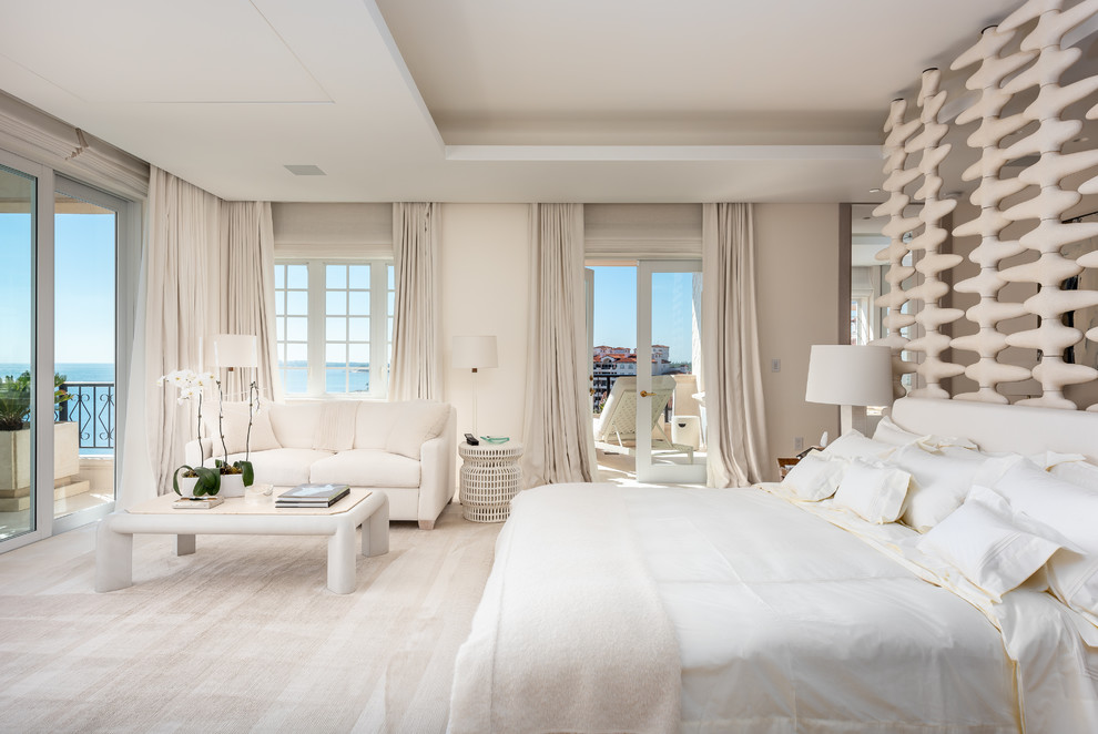 Inspiration for a large beach style master bedroom in Miami with white walls, carpet, no fireplace and beige floor.