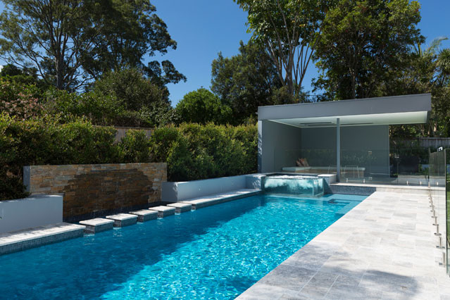 Large modern backyard rectangular lap pool in Sydney with natural stone pavers.