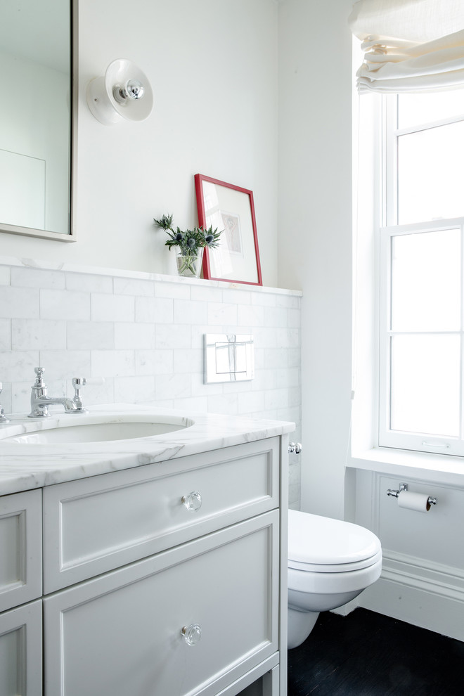 Inspiration for a large transitional master bathroom in New York with an undermount sink, white cabinets, marble benchtops, an alcove shower, white tile, white walls, raised-panel cabinets, a drop-in tub, a one-piece toilet, stone slab and concrete floors.