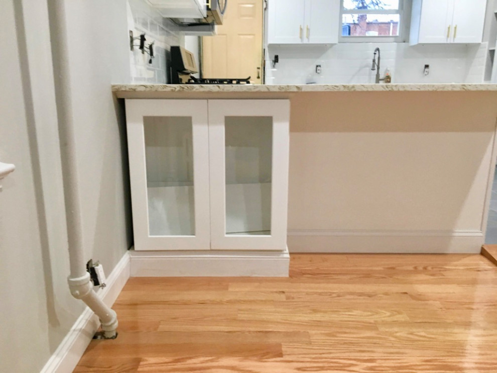 Foto på ett litet funkis vit kök, med en dubbel diskho, luckor med infälld panel, vita skåp, bänkskiva i kvarts, vitt stänkskydd, klinkergolv i keramik, en köksö och grått golv