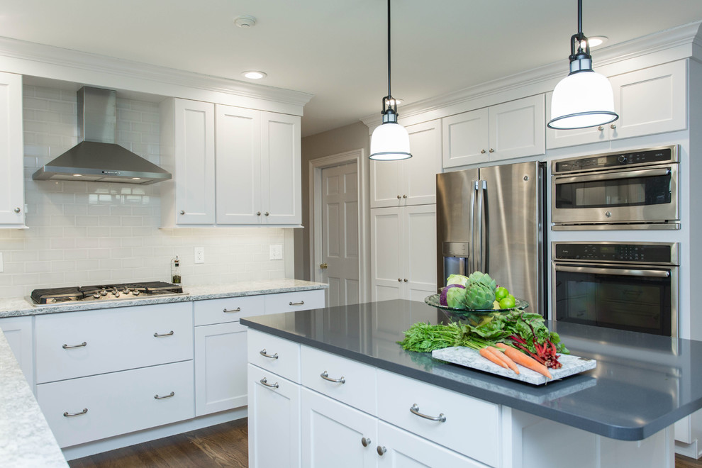 Enclosed kitchen - mid-sized transitional u-shaped dark wood floor enclosed kitchen idea in Boston with an undermount sink, recessed-panel cabinets, white cabinets, quartz countertops, gray backsplash, subway tile backsplash, stainless steel appliances and an island