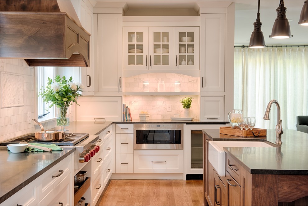 Inspiration for a mid-sized transitional l-shaped eat-in kitchen in Minneapolis with a farmhouse sink, flat-panel cabinets, white cabinets, granite benchtops, grey splashback, subway tile splashback, stainless steel appliances, medium hardwood floors and with island.