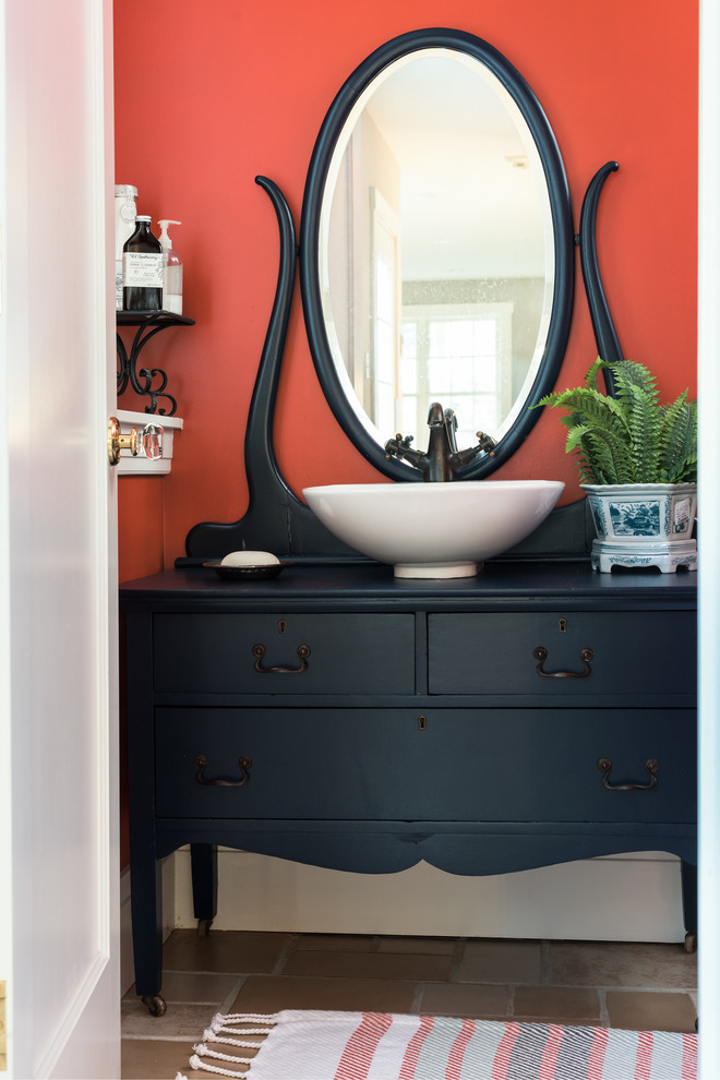 This is an example of a mid-sized eclectic kids bathroom in St Louis with furniture-like cabinets, blue cabinets, an alcove shower, orange tile, orange walls, cement tiles, a vessel sink, multi-coloured floor and a shower curtain.