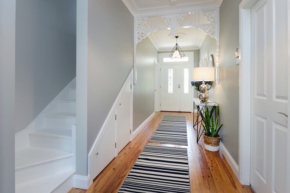 This is an example of an eclectic hallway in Sydney with grey walls, medium hardwood floors and brown floor.
