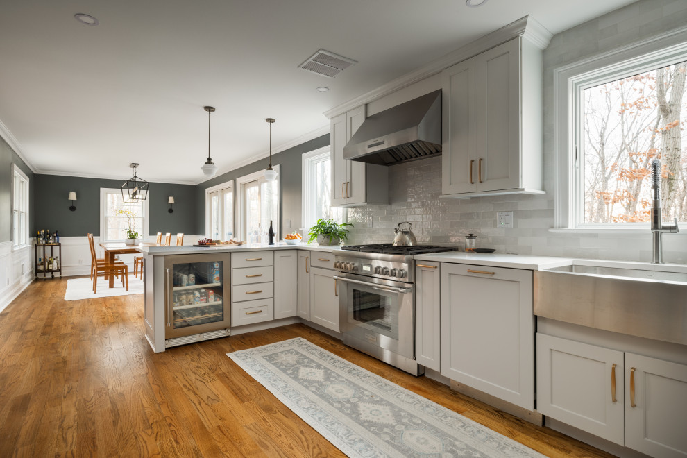 Exempel på ett mellanstort klassiskt vit vitt kök, med en rustik diskho, skåp i shakerstil, vita skåp, bänkskiva i kvarts, grått stänkskydd, stänkskydd i marmor, rostfria vitvaror, mellanmörkt trägolv, en halv köksö och brunt golv