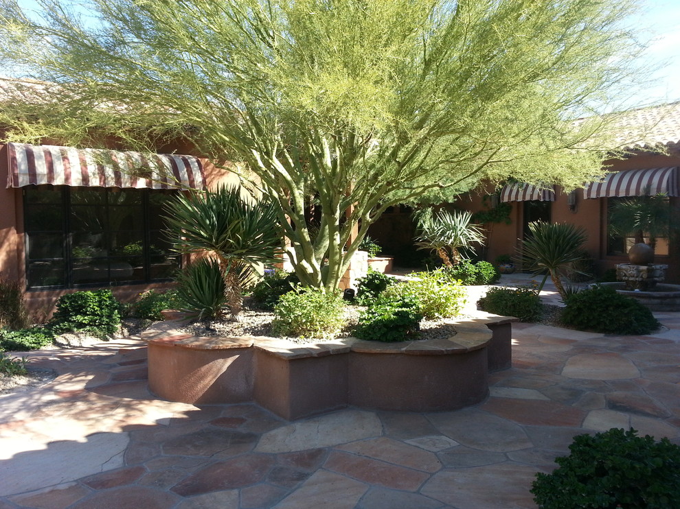 Inspiration for a large courtyard partial sun garden for summer in Phoenix with a retaining wall and natural stone pavers.