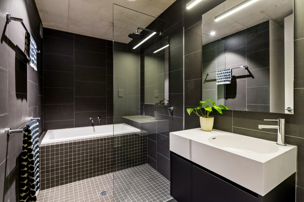 Mid-sized contemporary master wet room bathroom in Perth with flat-panel cabinets, black cabinets, a drop-in tub, black tile, porcelain tile, an integrated sink, grey floor and white benchtops.