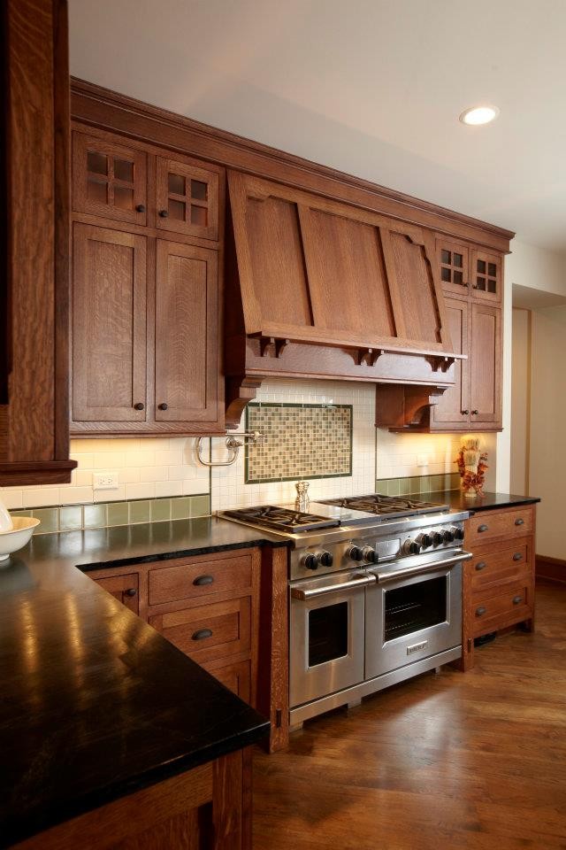 Design ideas for a large arts and crafts u-shaped eat-in kitchen in Chicago with shaker cabinets, dark wood cabinets, stainless steel appliances, dark hardwood floors, solid surface benchtops, multi-coloured splashback and with island.