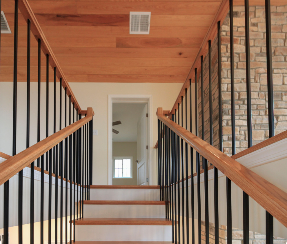 This is an example of a large transitional wood floating staircase in DC Metro with wood risers, mixed railing and planked wall panelling.