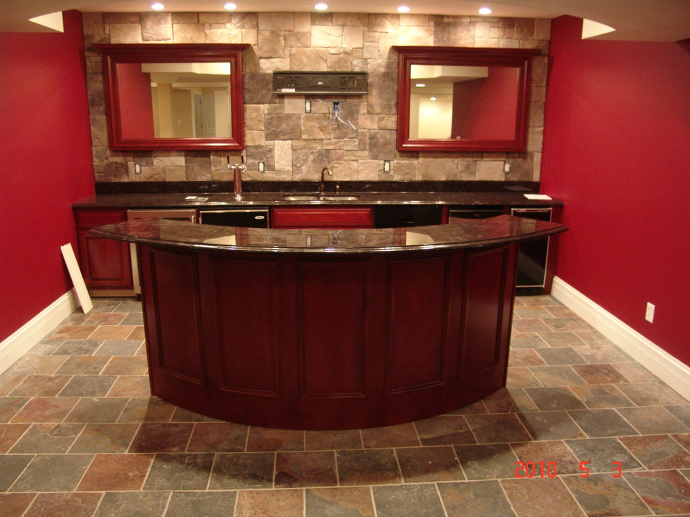 Photo of a large traditional single-wall wet bar in St Louis with an undermount sink, recessed-panel cabinets, medium wood cabinets, beige splashback, stone tile splashback and ceramic floors.